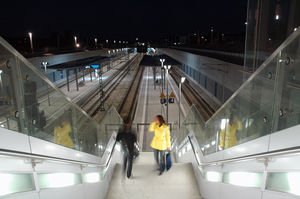 Nachaufnahme vom tiefergelegten Bahnhof, zwei Personen laufen gerade die Treppen vom tiefergelegten Gleis nach oben