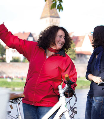 Eine Stadtführerin mit Fahrrad erklärt etwas