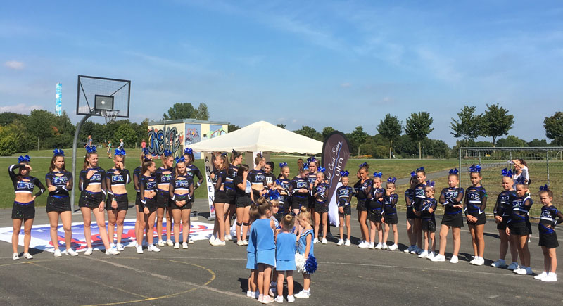 Eine Gruppe von Cheerleadern steht in einem Halbkreis auf dem Hartplatz im Sport- und Freizeitpark Wiley