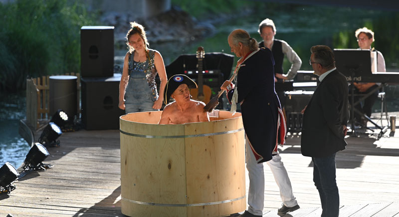 Foto von der Aufführung des Bürgertheaters "Napoleon geht baden":  Ein Schauspieler mit einem Napoelonshut sitzt in einem Waschzuber