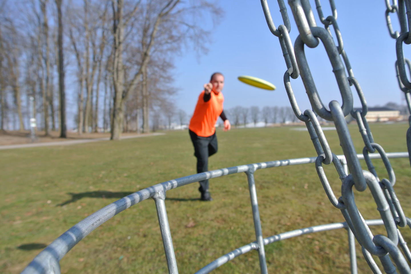 Ein Disc Golf Spieler wirft eine Disc Golf Scheibe in einen Disc Golf Korb
