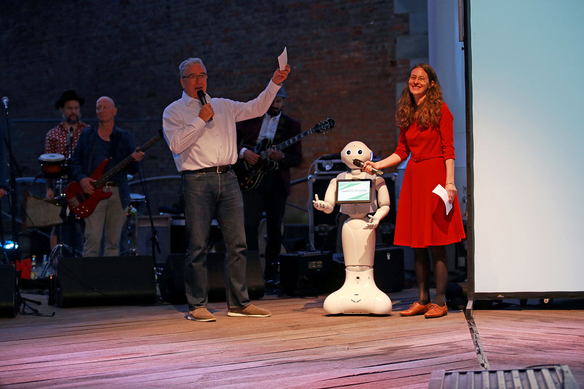 Die Moderatorin, Oberbürgermeister Gerold Noerenberg und Eddi, ein humanoider Roboter, auf der Bühne