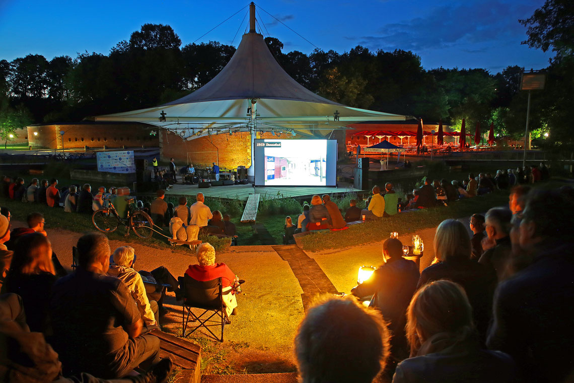 Blick aus dem Publikum bei der nächtlichen Filmvorführung auf der Veranstaltungsbühne im Neu-Ulmer Glacis-Park