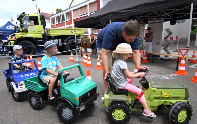Drei Kinder fahren hintereinander auf drei Kinder-Fahrzeugen